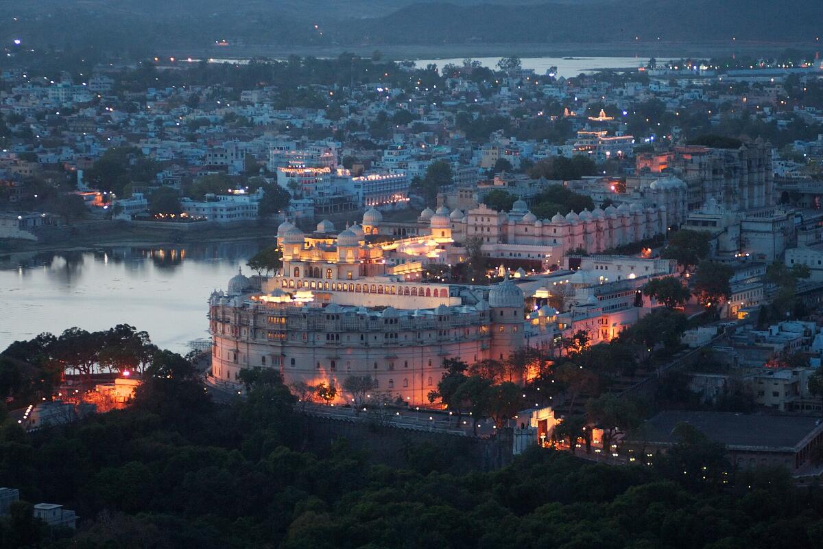 The City Palace of Udaipur lit up in the evening above Lake Pichola
