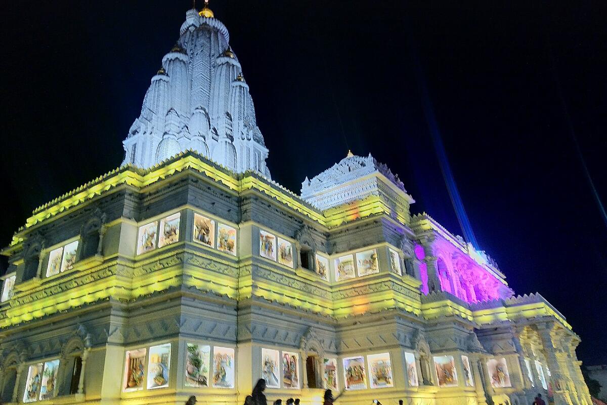 The marble Prem Mandir temple in Vrindavan lit up in yellow and green at night