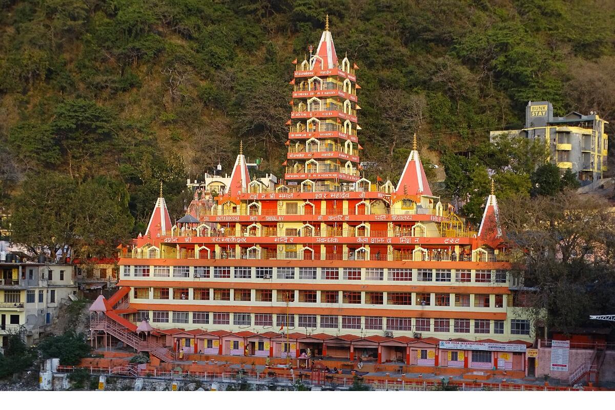 A temple tower rising above the Ganga at Rishikesh with forested hills behind