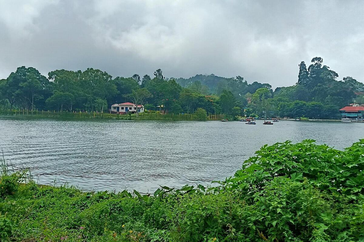 Yercaud lake surrounded by green trees under a cloudy sky