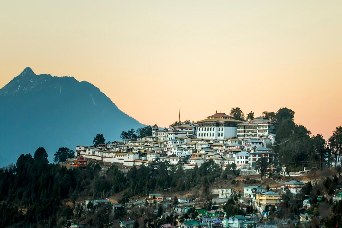 Tawang Monastery and the town on a hillside below a mountain peak at dusk